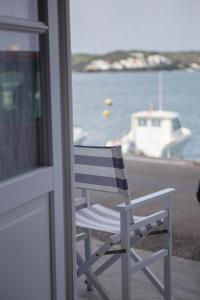 een witte stoel op een balkon met een boot in het water bij Fonduco in Mahón