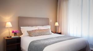 a bedroom with a large bed and two lamps at Lagoon Beach Hotel Apartments in Cape Town