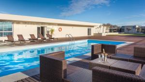 a swimming pool with wicker chairs and a table at Lagoon Beach Hotel Apartments in Cape Town