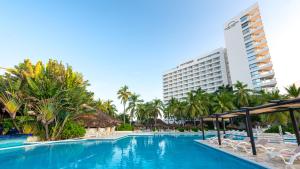 a swimming pool with chairs and palm trees and buildings at Park Royal Beach Ixtapa - All Inclusive in Ixtapa