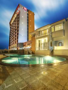 a hotel with a swimming pool in front of a building at Ibis Padang in Padang