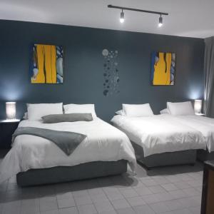 a bedroom with two beds and two paintings on the wall at Durban Beachfront 10 South Apartments 1404 in Durban