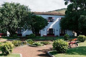 um edifício branco com árvores e bancos num quintal em Monte Ingles em Ponta Delgada