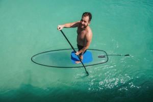 a man is rowing a paddle board in the water at Siyam World Maldives - 24-Hour Premium All-inclusive with Free Transfer in Dhigurah