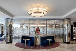 a lobby with a blue couch and two tables and a chandelier at The Royce in Melbourne