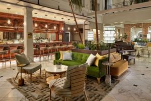 The Tremont House, Galveston, a Tribute Portfolio Hotel في جالفيستون: لوبي فيه اريكه خضراء وكراسي وبار