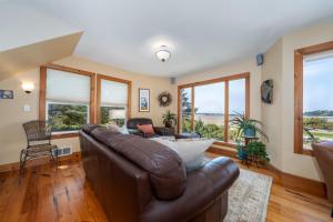 a living room with a leather couch and windows at Siletz Bay Beach House in Lincoln City