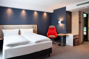 ein Schlafzimmer mit einem Bett und einem roten Stuhl in der Unterkunft Holiday Inn Express Fürth by IHG in Fürth