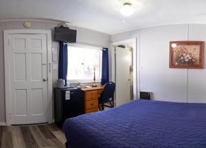 a bedroom with a blue bed and a desk and a window at Belle Isle Motel in Bar Harbor