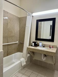 bagno con vasca, lavandino e specchio di Baymont by Wyndham Galveston a Galveston