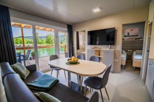 uma sala de estar com uma mesa e um sofá e uma cozinha em DELUXE Lake View Mobile Homes with Thermal Riviera Tickets em Čatež ob Savi