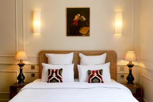 a bedroom with a bed with two lamps and a painting at Hôtel Bristol Pau in Pau