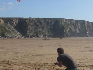 a man is flying a kite on the beach at Trevarrian Lodge in Newquay