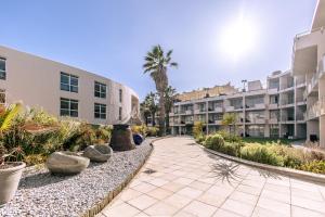 a walkway in front of a building with palm trees at Lagoon Beach Hotel Apartments in Cape Town