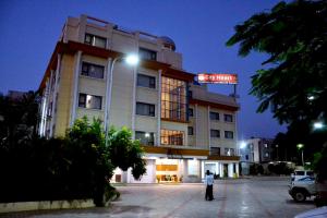 a man standing in front of a building at night at Hotel City Heart Shirdi in Shirdi