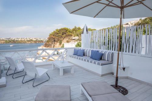 een patio met een bank, stoelen en een parasol bij Fonduco in Mahón