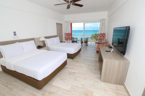 a bedroom with two beds and a flat screen tv at Grand Decameron Cornwall Beach, A Trademark All-Inclusive Resort in Montego Bay