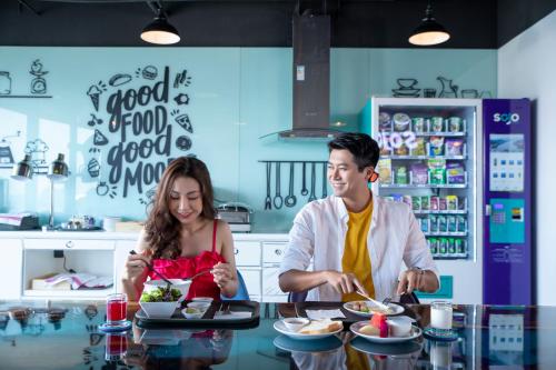 Ein Mann und eine Frau bereiten Essen in einer Küche vor. in der Unterkunft SOJO Hotel Ha Long in Hạ Long