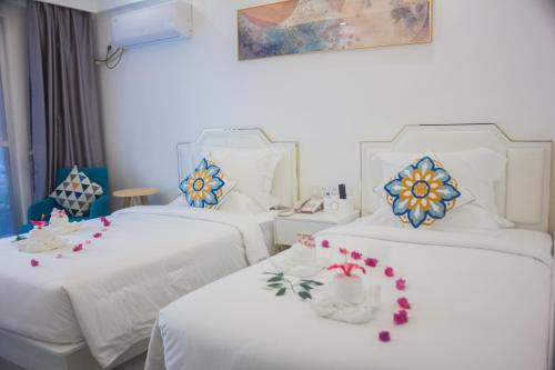 two beds in a hotel room with flowers on them at Bohol Dolphin Bay Resort in Panglao Island