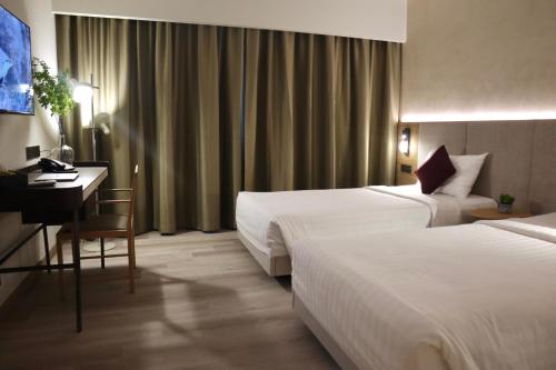 a hotel room with two beds and a desk at The Brunei Hotel in Bandar Seri Begawan