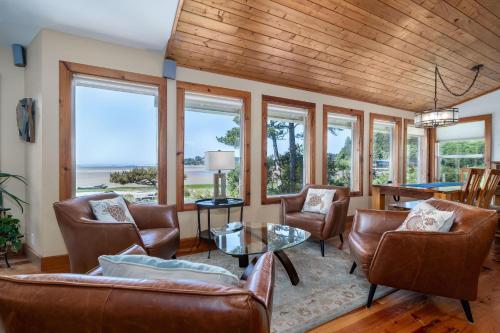 a living room with leather furniture and windows at Siletz Bay Beach House in Lincoln City