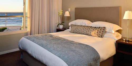 a bedroom with a bed with a view of the ocean at Lagoon Beach Hotel Apartments in Cape Town