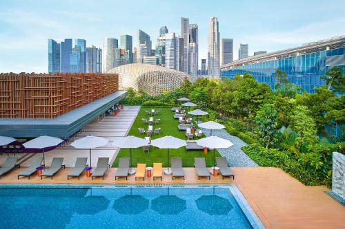 a pool with chairs and umbrellas and a city skyline at PARKROYAL COLLECTION Marina Bay, Singapore in Singapore