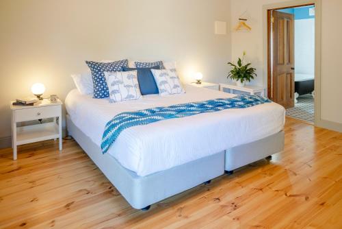 a bedroom with a large bed with blue and white pillows at Willunga Gallery Cabins in Willunga