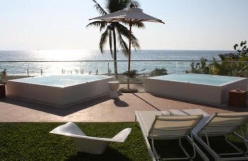 una piscina y dos sillas y una sombrilla junto al océano en Icon Vallarta, en Puerto Vallarta