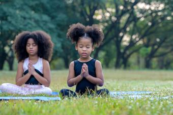 cute children meditating on yoga mat outdoor