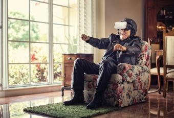 Elderly person dressed in motorcycle gear, playing VR