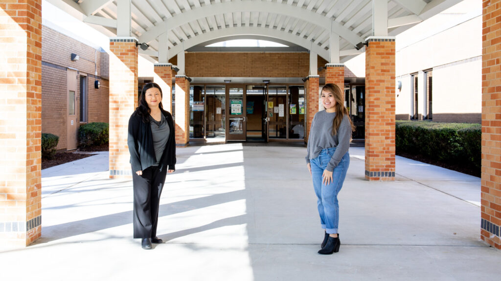 A principal and a young lady who is a former student and now an aspiring teacher stand outside the front of Martin Elementary School.