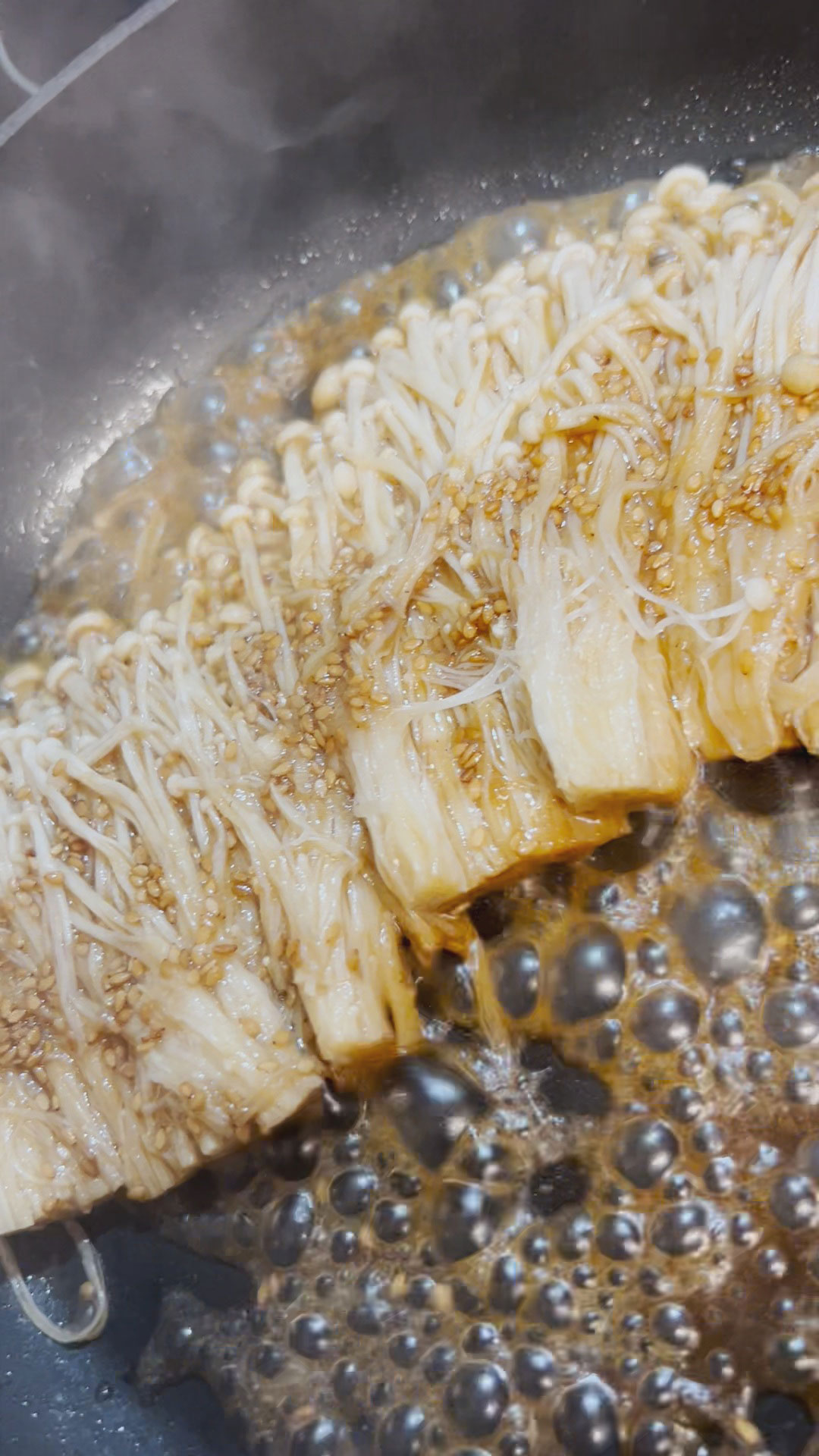 Soy garlic enoki mushrooms sizzling in a pan 