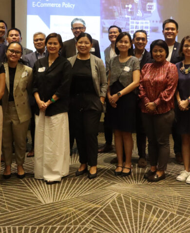 Image of a large group of team members smiling and standing in front of a presentation.