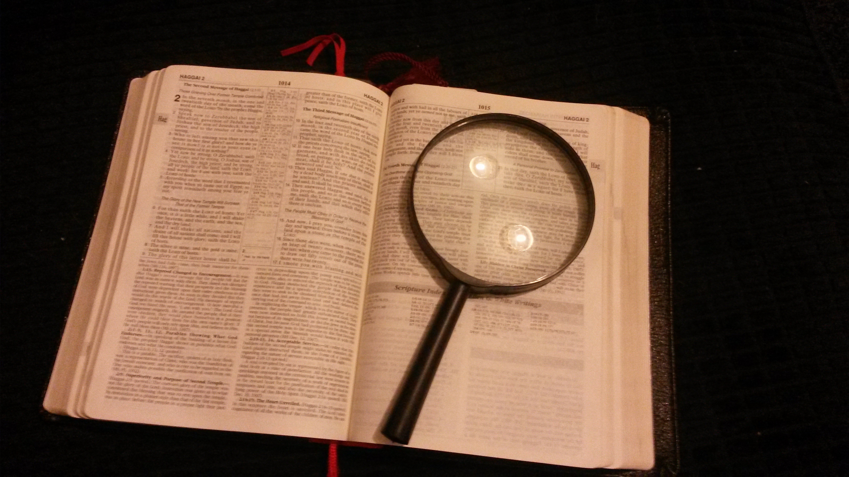 Opened bible and magnifying glass free image.