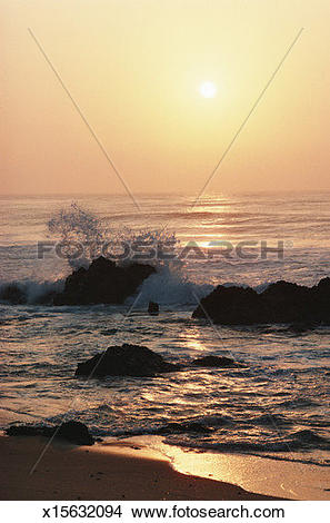 Stock Photo of Waves breaking on rocks and surf washing over beach.