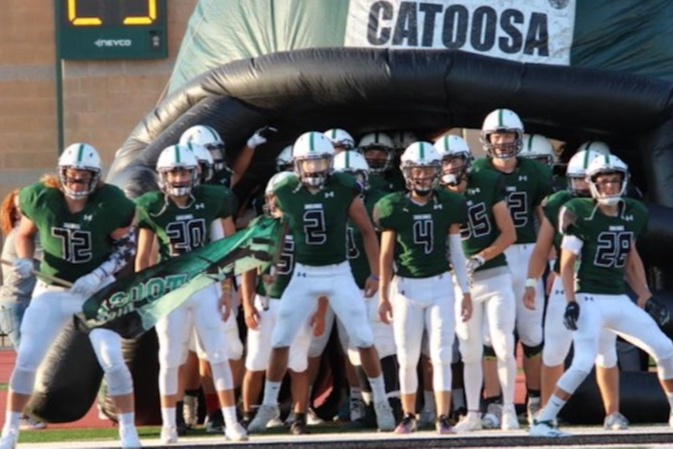 catoosa football team running out of low up football helmet wearing green jerseys