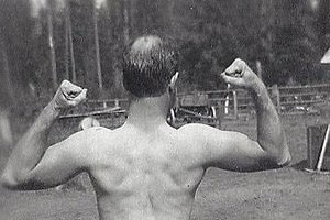 An old photo of a balding man flexing his biceps.