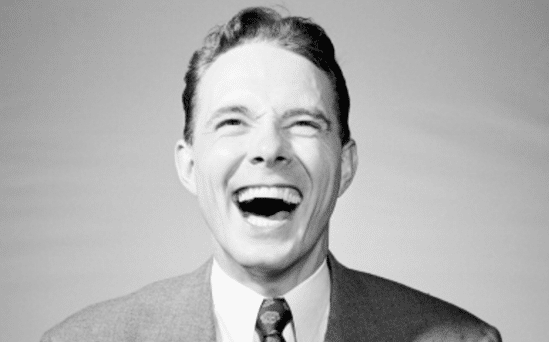 A black and white photo of a man laughing, captured in 1928.