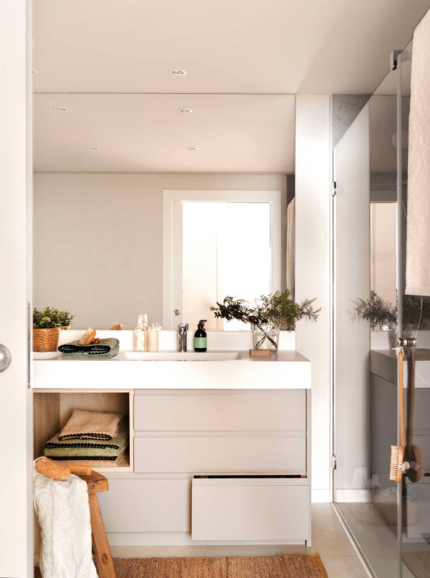 Baño moderno con mueble gris y alfombra de fibra natural.