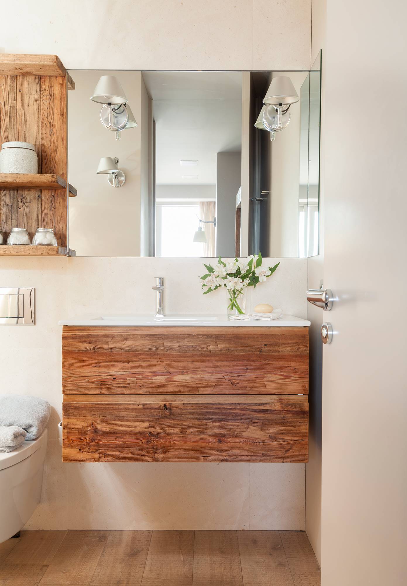 Baño con mueble suspendido en madera y espejo grande. 