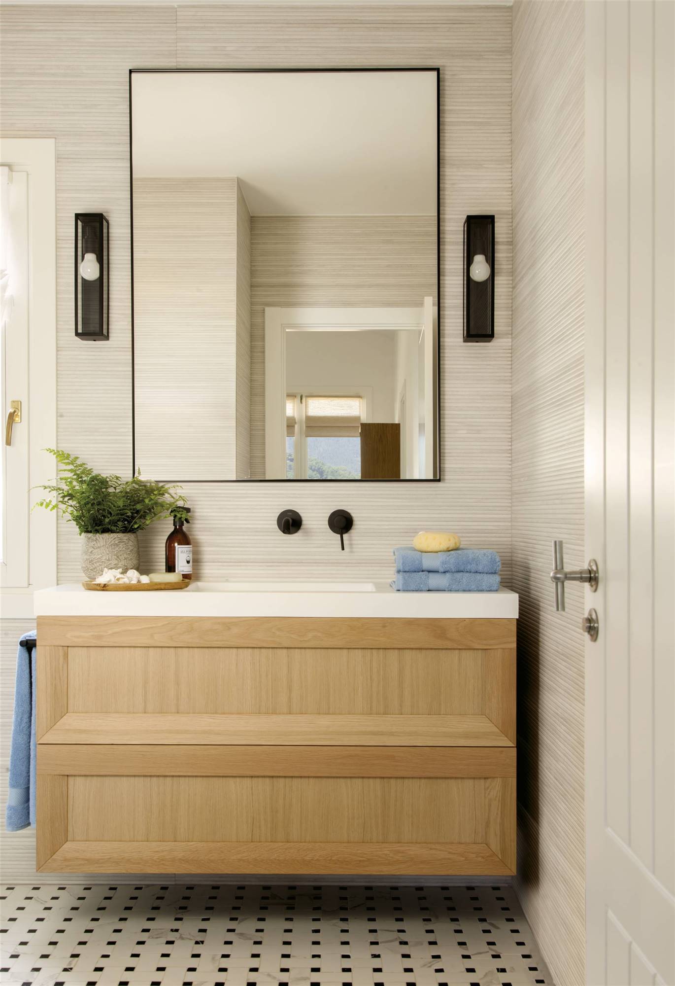 Baño con mueble de madera, espejo rectangular y apliques a cada lado