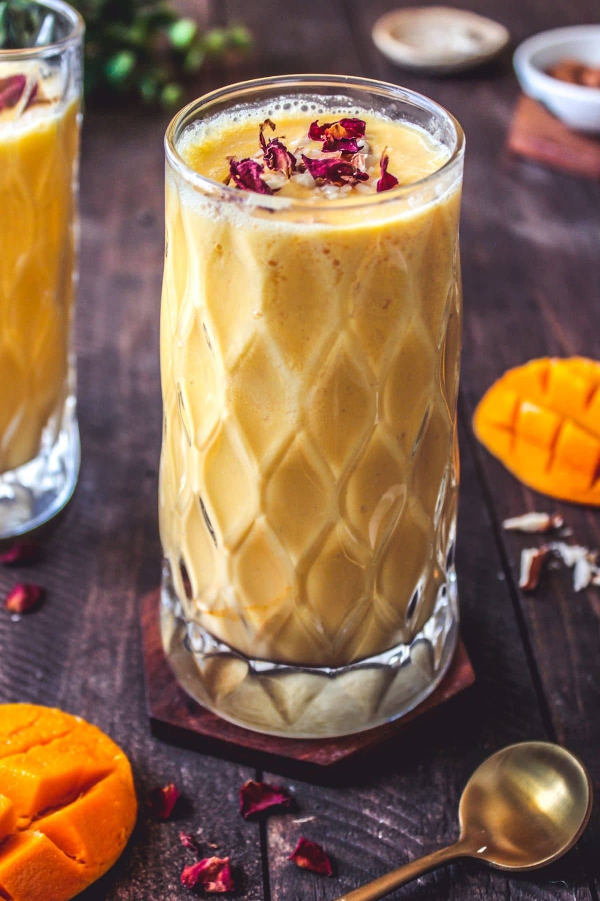 Tall clear beveled glass filled with lassi on wood table