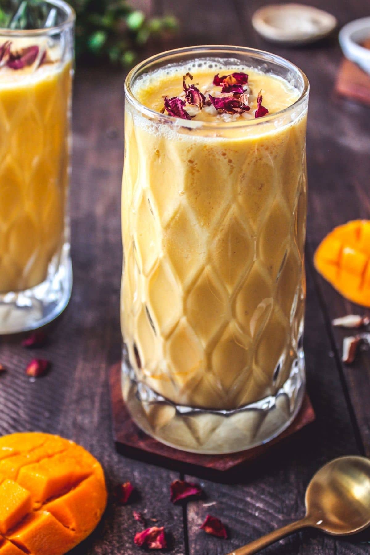 Beveled glasses of mango lassi with rose petals on top