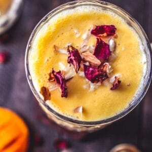 Overhead picture of mango lassi in glass sitting on wooden table