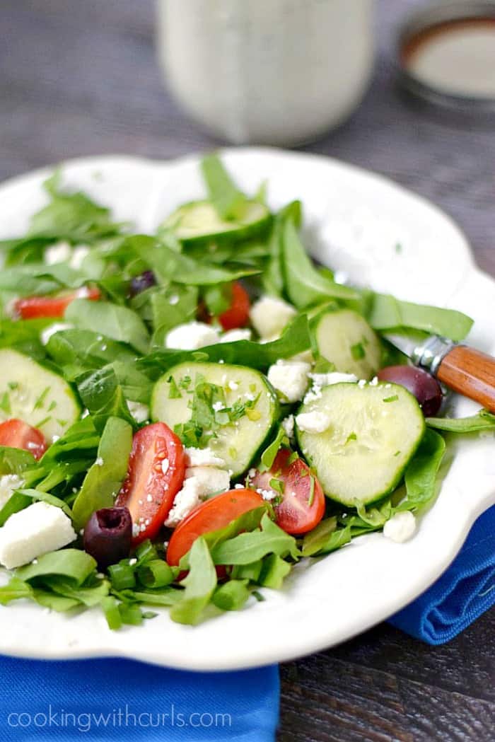 A fresh Greek Salad on a white plate sitting on a bright blue napkin