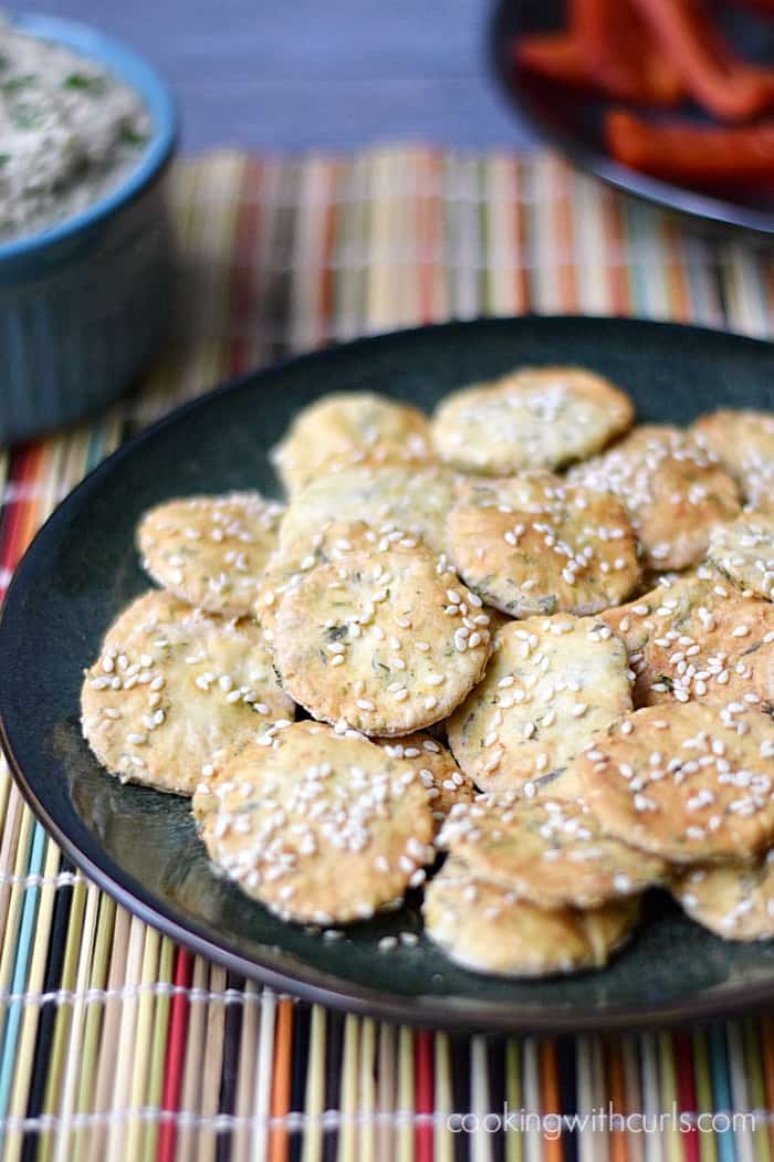 Sesame Crackers on a dark plate sitting on a rainbow colored place mat