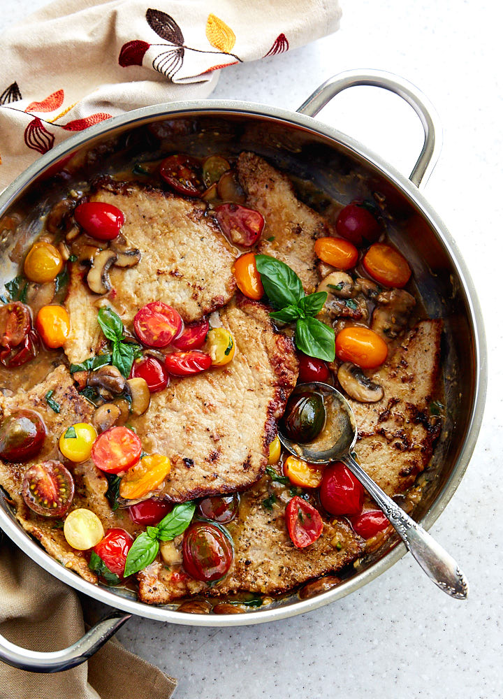 Veal scallopini in a pan with mushroom sauce.