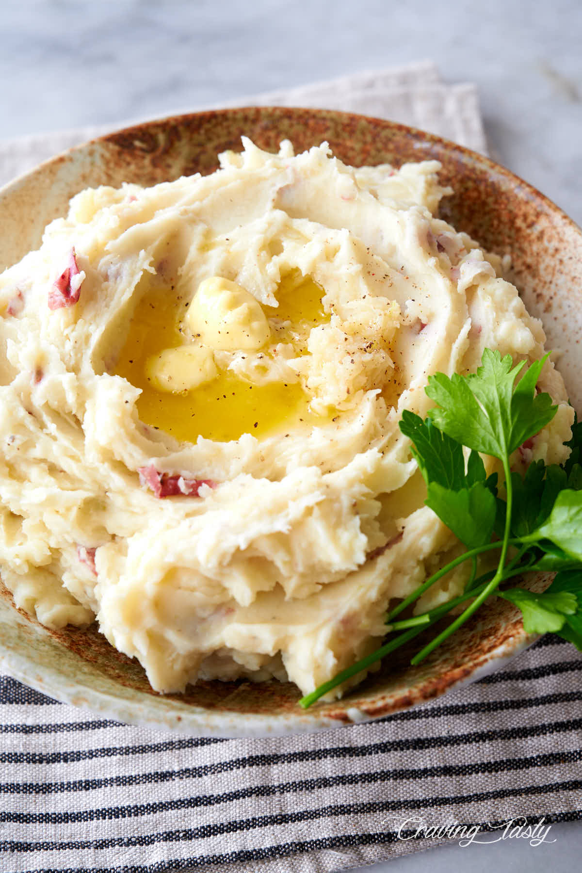 Close up of mashed red potatoes with mashed garlic on top and melted butter.