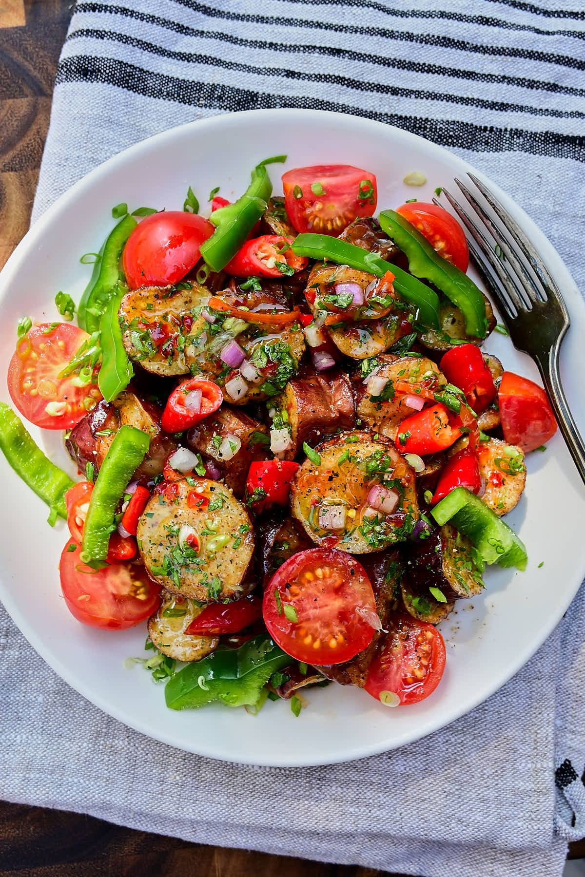 Delicious fried eggplant seasoned with red chili sauce, chopper herbs and served with bell peppers, sweet chili peppers and cherry tomatoes.